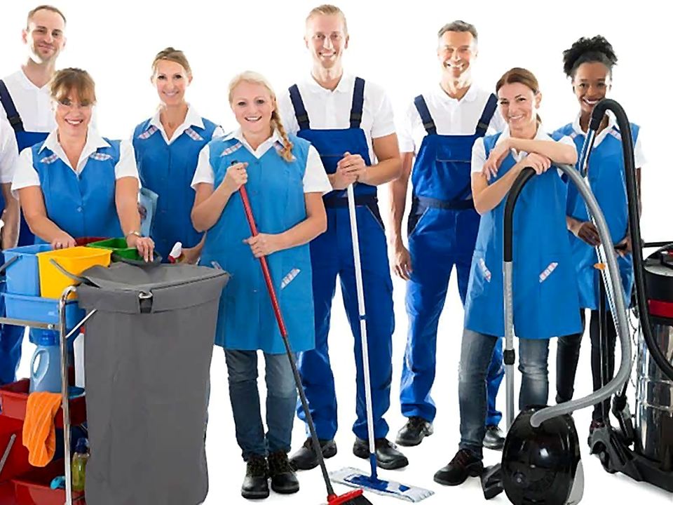 Cleaning team in work clothes with a cleaning trolley, mops and vacuum cleaners