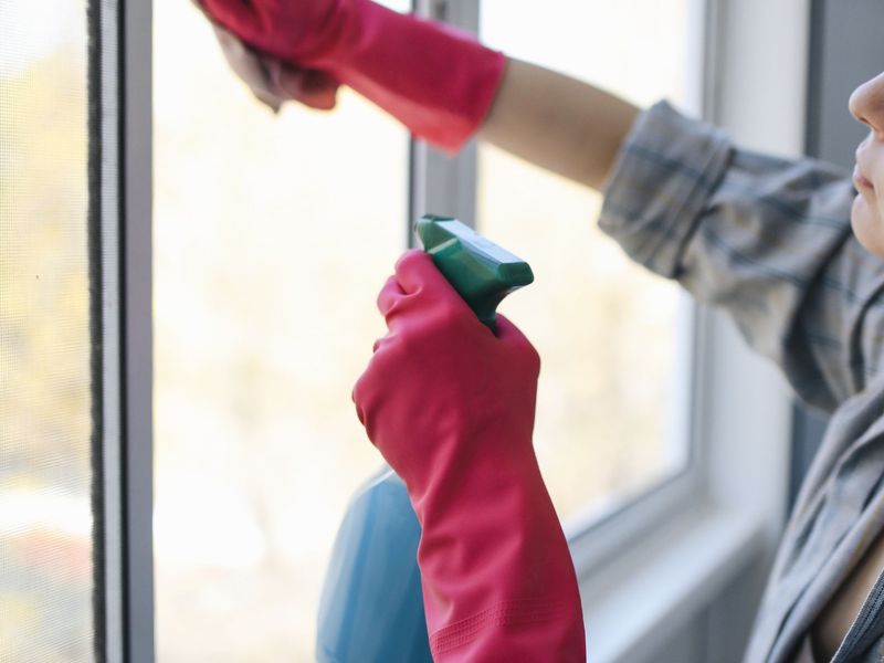 Cleaning a window with a cloth and a spray bottle